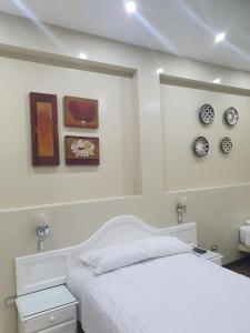 ein Schlafzimmer mit einem weißen Bett und Uhren an der Wand in der Unterkunft HOTEL CENTRAL in Chiclayo