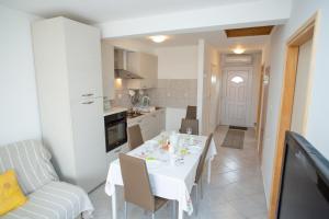 una cucina e una sala da pranzo con tavolo e sedie bianchi di Apartment Tara with pool a Povljana (Pogliana)