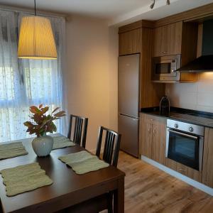 a kitchen with a wooden table with chairs and a dining room at Apartamentos Antonia in Cuzcurrita-Río Tirón