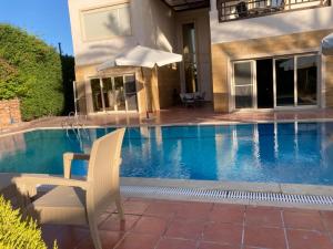 Relaxation Villa with private pool في الإسكندرية: منزل مع مسبح وكرسي ومظلة