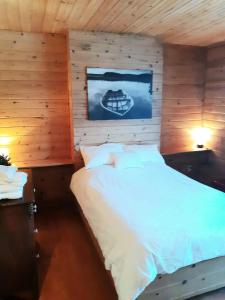 1 dormitorio con 1 cama blanca en una pared de madera en Auberge Ma Maison, en Sainte-Melanie