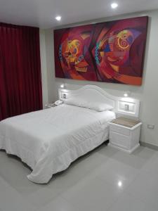 奇克拉約的住宿－HOTEL CENTRAL，卧室配有白色的床和墙上的绘画作品