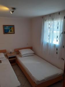 two beds in a room with a window at Apartman Sanjković in Rovinjsko Selo