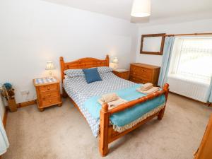1 dormitorio con cama de madera y ventana en Cefn Werthyd Farmhouse, en Caernarfon