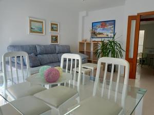 sala de estar con mesa de cristal y sillas en Apartamentos Coralba - Dúplex Bahía de Cádiz, en San Fernando