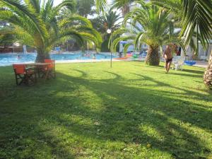 a person walking by a pool with a table and palm trees at Alessandro in Sidari