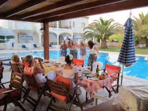 a group of women sitting around a table by a pool at Alessandro in Sidari