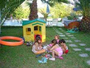 a group of girls sitting in the grass near a toy house at Alessandro in Sidari