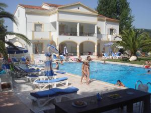 a person standing in a swimming pool next to a house at Alessandro in Sidari