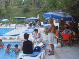 a group of people sitting around a swimming pool at Alessandro in Sidari