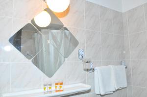 een badkamer met een grote spiegel aan de muur bij Oasis Hotel Theodoros & Litsa Galaris in Agia Marina Aegina