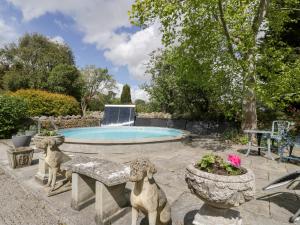 a pool with two statues of dogs in a yard at The Granary in Edington