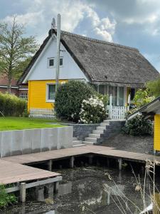 una casa amarilla con un estanque delante de ella en Ferienhaus Butterblume, en Südbrookmerland