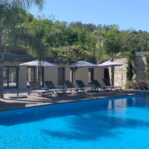 a swimming pool with lounge chairs and umbrellas at Quinta de Santa Ana, em Vizela in Infias