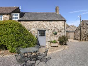 a stone house with a table and chairs in front of it at Stable 1 in Llanbedrog