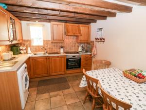 a kitchen with wooden cabinets and a table with a sink at Stable 1 in Llanbedrog