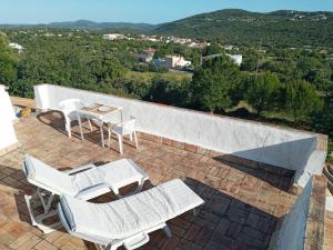 a patio with white chairs and a table and a view at Paz e Natureza in São Brás de Alportel