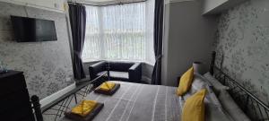 um quarto com uma cama com almofadas amarelas e uma janela em The Roslyn Guest House em Paignton