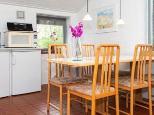 une cuisine avec une table, des chaises et un vase de fleurs dans l'établissement 6 person holiday home in Hejls, à Hejls