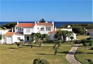 a large white house with the ocean in the background at Favorite at Senhora da Rocha in Porches