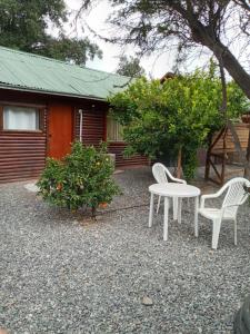 two chairs and a table in front of a house at Cabaña Cerezo in Guayacán