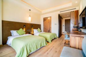 una camera d'albergo con due letti con lenzuola verdi di Jinling Onejoy Hotel a Nanjing