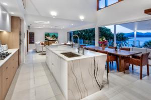 ハミルトン島にあるLotus House on Hamilton Island by HIHAの大きな窓付きのキッチン、ダイニングルームが備わります。