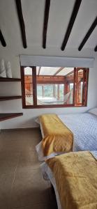two beds in a room with a large window at Villa Monica HR in Villa de Leyva