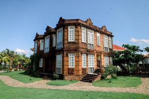 a large brick building with white windows on a field of grass at Las Casas Filipinas de Acuzar in Bagac
