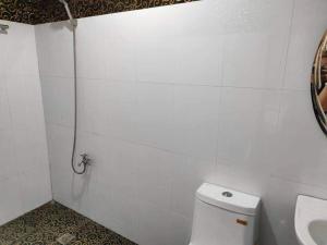 y baño de azulejos blancos con aseo y ducha. en RedDoorz @ Villa E Mansion, en Vigan