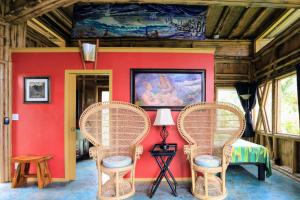 two wicker chairs in a room with a red wall at Kalani Oceanside Retreat in Pahoa