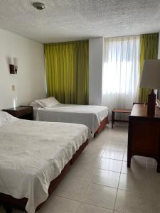 a hotel room with two beds and a window at Hotel Bachue Girardot in Girardot