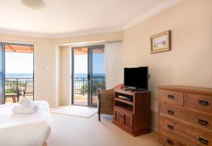 a bedroom with a bed and a flat screen tv at Breakers 1 10 LJHooker Yamba in Yamba
