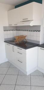 een keuken met witte kasten en een zwart aanrecht bij Studio indépendant dans maison individuelle in Brax