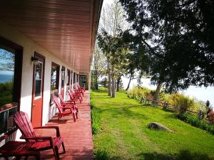 a row of chairs sitting on the porch of a house at Auberge La Coudriere (Cool Hotel) in L'Isle-aux-Coudres