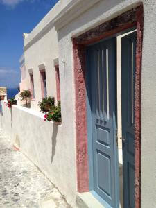 a white building with a blue door and windows at Marcos Rooms in Oia