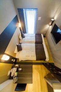 a loft bedroom with two beds and a window at HOTEL SUITE HIROSHIMA YOKOGAWA in Hiroshima