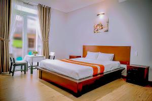 a bedroom with a bed and a table and a window at Jolie House in Da Lat