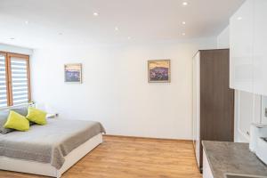 a bedroom with white walls and a bed with yellow pillows at Shushi's Central Studio Apartment in Plovdiv