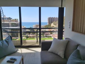 Tyba Deluxe Apartment في أليكانتي: غرفة معيشة مع أريكة وإطلالة على المحيط
