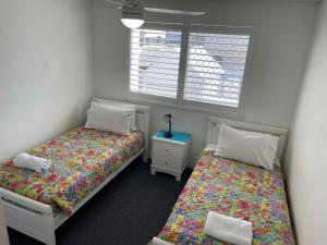 two beds in a small room with a window at Mainsail 3 in Mooloolaba