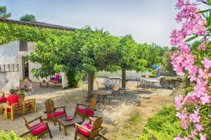 un patio con mesas, sillas, árboles y flores en Chambres d'hôtes & Spa le Relais de la Cavayere, en Carcassonne