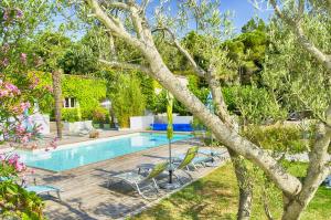 a swimming pool in a yard with chairs and a tree at Chambres d'hôtes & Spa le Relais de la Cavayere in Carcassonne
