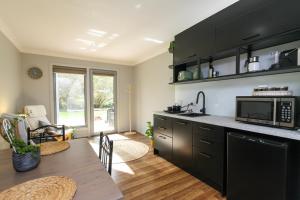 a kitchen with black cabinets and a table with a microwave at Riverside Haven in Healesville