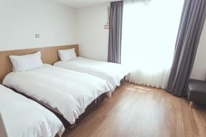 two beds in a room with a window at Kenny Stay Jeju Mosulpo in Seogwipo