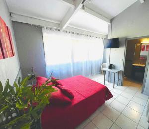 a bedroom with a red bed with a red blanket at L organdi in Cornebarrieu