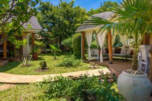 a garden with a gazebo with a couch at private pool cottage diani beach in Diani Beach