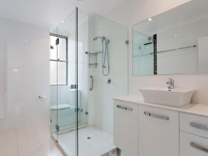 a white bathroom with a sink and a shower at Ocean Shores 12 Waterfront Unit with Sensational Water Views WiFI and Air Conditioning in Nelson Bay