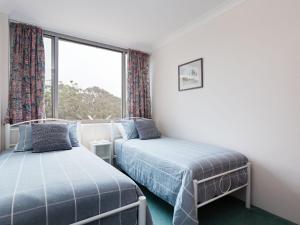 two beds in a room with a window at Ocean Shores 12 Waterfront Unit with Sensational Water Views WiFI and Air Conditioning in Nelson Bay