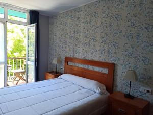 a bedroom with a large bed and a balcony at Hotel Águila Real in Cangas de Onís